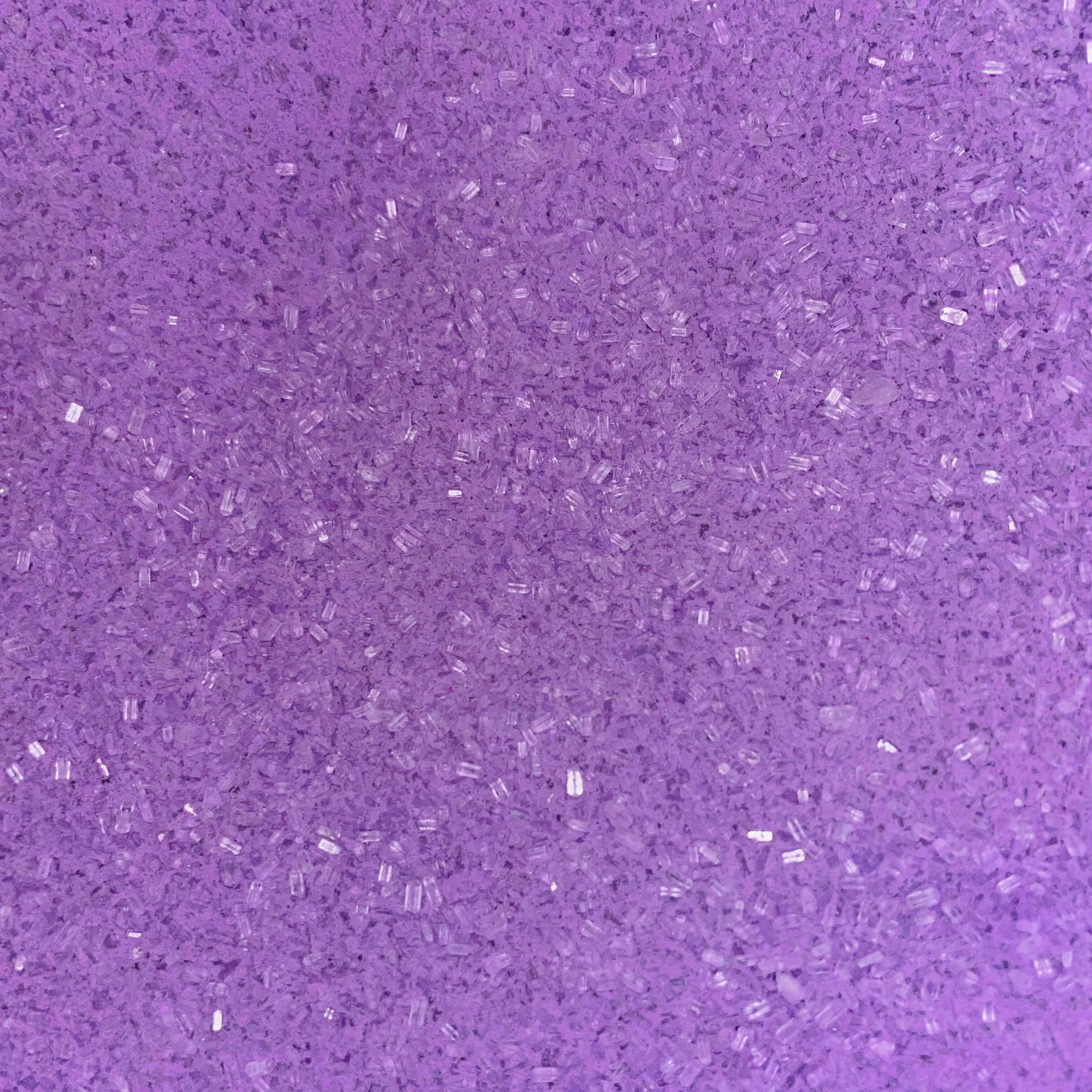 Close-up of fine, bright purple bath soak crystals with a slightly coarse texture and a sparkly, granular appearance