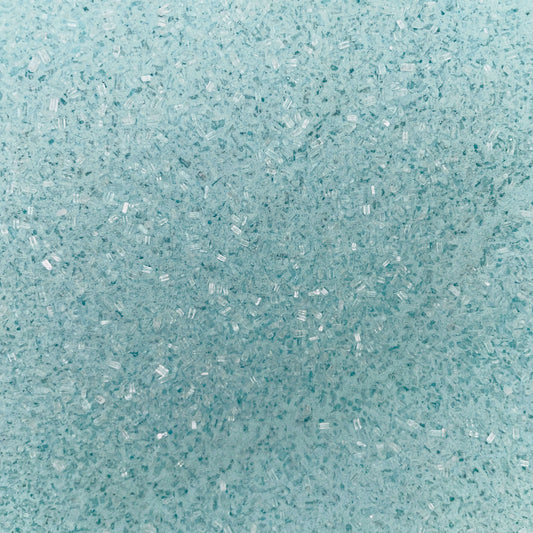 Close-up of fine, light blue bath soak crystals with a slightly coarse texture and a sparkly, granular appearance