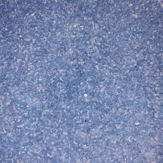 Close-up of fine, light purple bath soak crystals with a slightly coarse texture and a sparkly, granular appearance