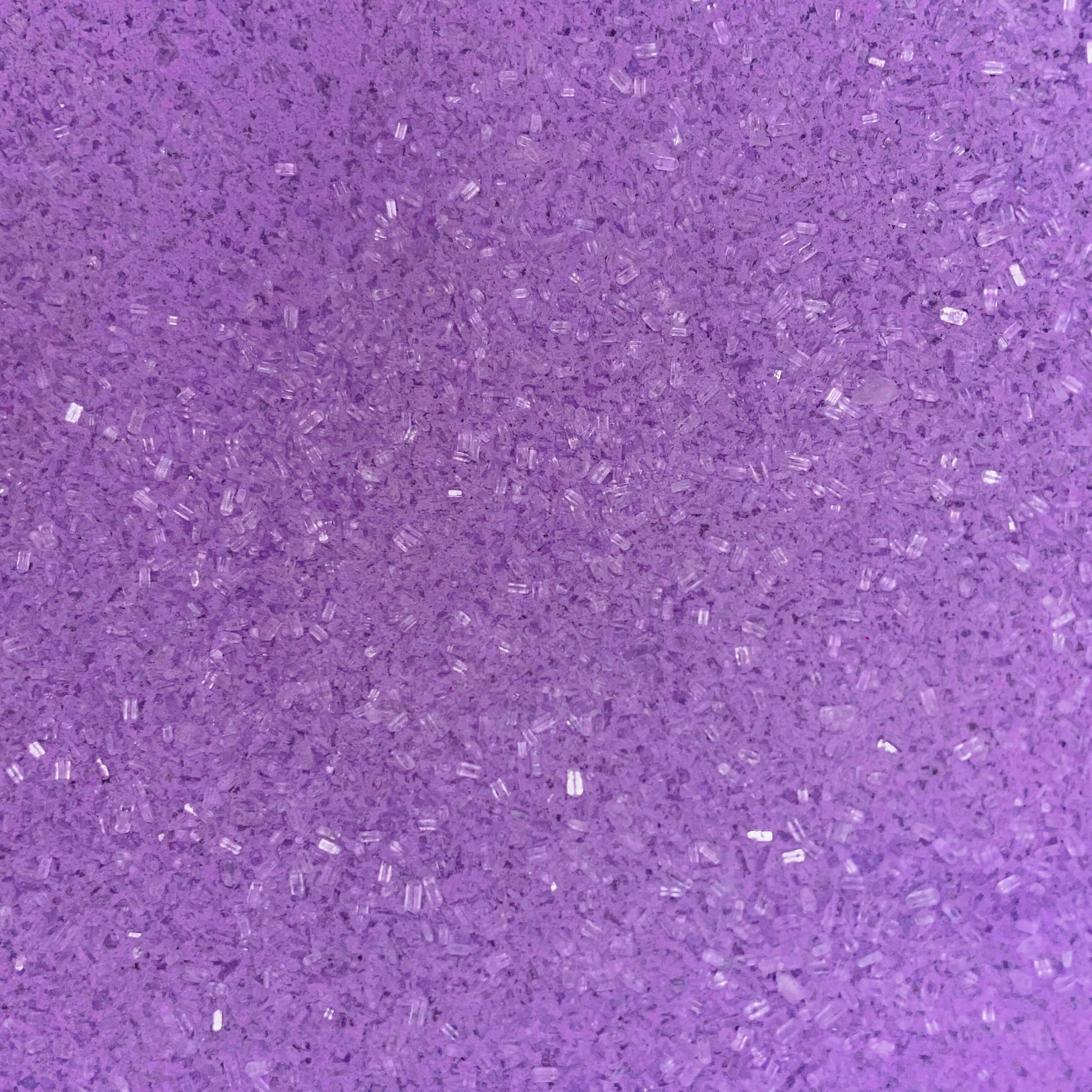 Close-up of fine, bright purple bath soak crystals with a slightly coarse texture and a sparkly, granular appearance